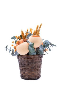 Cesto natural oscuro con flores secas y preservadas en tonos naranjas